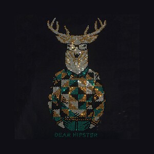 Könnte beinhalten: Ein Strass-Grafikdesign auf schwarzem Hintergrund zeigt einen Hirschkopf mit Geweih und Brille, der ein geometrisch gemustertes Hemd in den Farben Petrol, Gold und Weiß trägt. Der Text DEAR HIPSTER ist in Petrol unter der Hirschfigur gedruckt.