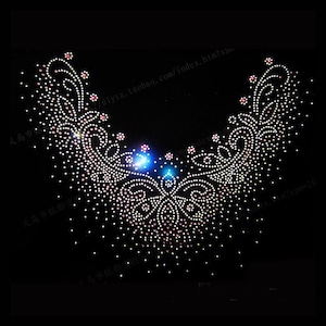 May include: A V-shaped neckline applique composed of numerous small, reflective white and pink rhinestones arranged in a symmetrical, intricate swirling floral pattern against a solid black background, creating a decorative embellishment.