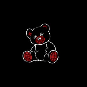 Op de afbeelding: Een witte en rode strass teddybeer applique. De beer zit met zijn armen uitgestrekt en heeft een rode neus en ogen.