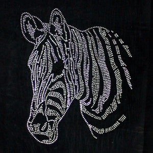 May include: A black fabric surface featuring a zebra head design created with small, reflective silver-toned studs. The pattern follows the natural striped markings of a zebra, with the studs arranged to form the ears, face, and neck profile.