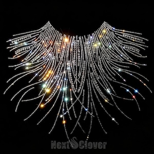 May include: A decorative collar appliqué composed of numerous clear, reflective rhinestones arranged in a radiating, fan-like pattern against a black background. The design features curved lines of crystals that taper downwards. Text reads NextClover.
