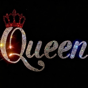 Może przedstawiać: Wzór z dżetów przedstawiający słowo Queen napisane kursywą. Litery składają się z przezroczystych, błyszczących kryształków, a ikona korony umieszczona nad literą Q jest wypełniona żywymi, czerwonymi dżetami.