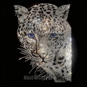 Puede incluir: Un diseño de cabeza de leopardo creado con pedrería transparente y plateada sobre un fondo negro. El leopardo presenta dos ojos de pedrería azul brillante y bigotes largos. El texto NextSlover es visible en pedrería plateada en la parte inferior.