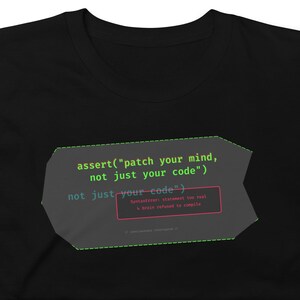May include: Black t-shirt with a graphic that reads "assert("patch your mind, not just your code")" in green and white text. The design includes a red box with the text "SyntaxError: Statement too real, brain refused to compile."