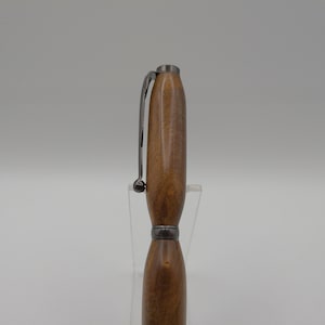 May include: A wooden pen with a black metal clip and a brown wood grain pattern.