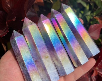 May include: Six iridescent purple crystal points with a rainbow sheen. The points are arranged in a fan shape, with the tips of the points pointing towards the right side of the image.