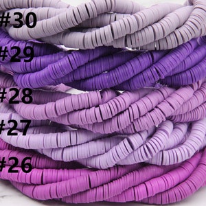 May include: A close-up of a stack of purple and lavender colored polymer clay beads. The beads are arranged in a gradient from light lavender to dark purple. The beads are labeled with numbers 26 through 30.