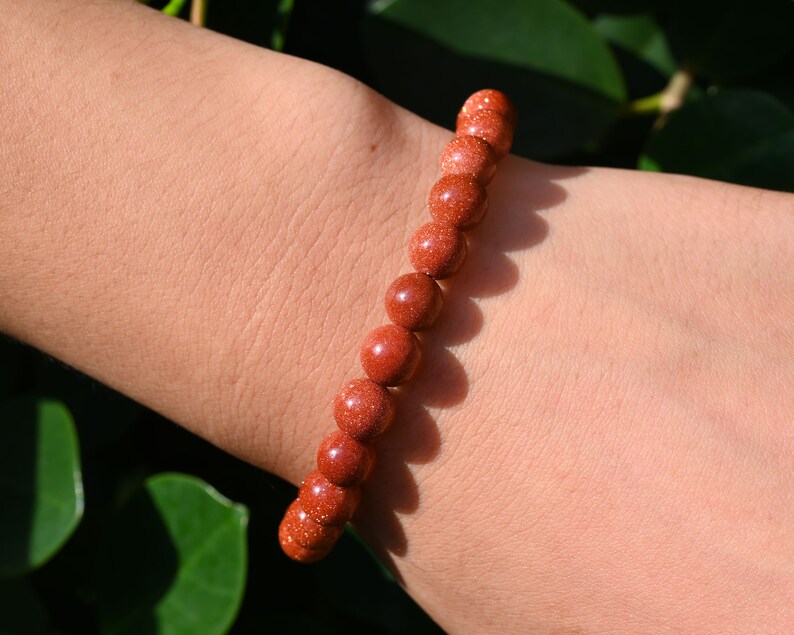 Puede incluir: Un brazalete de cuentas marrones hecho de cuentas de piedra arenisca natural. El brazalete se lleva en la mu&ntilde;eca.