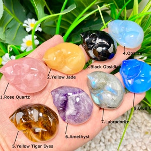 May include: Eight different types of sleeping cat figurines carved from various gemstones, including rose quartz, yellow jade, black obsidian, opalite, amethyst, tiger's eye, labradorite, and blue opalite.