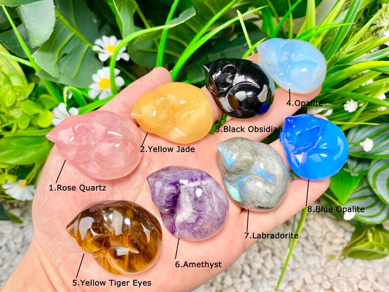 May include: Eight different types of sleeping cat figurines carved from various gemstones, including rose quartz, yellow jade, black obsidian, opalite, amethyst, tiger's eye, labradorite, and blue opalite.