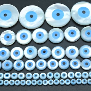 May include: Assortment of white and blue evil eye beads, ranging in size from small to large. The beads are made of mother of pearl and have a blue enamel eye with a black pupil.