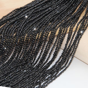 May include: A strand of black faceted beads, likely made of glass or crystal, for jewelry making. The beads are small and uniform in size, creating a sleek and elegant look.