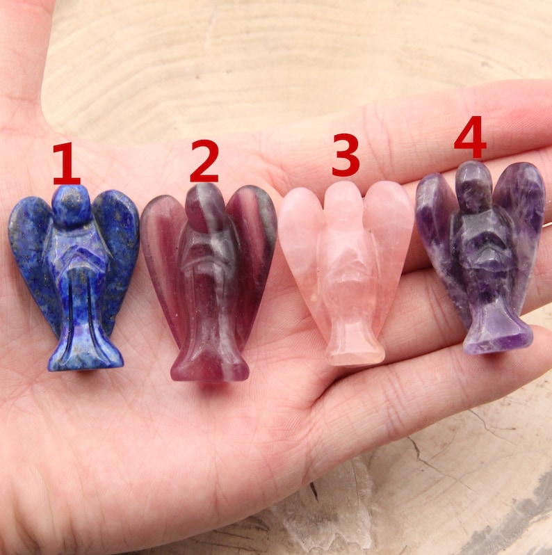 May include: Four angel figurines carved from different types of gemstones. The figurines are numbered 1 through 4. Figurine 1 is blue, figurine 2 is purple, figurine 3 is pink, and figurine 4 is amethyst.