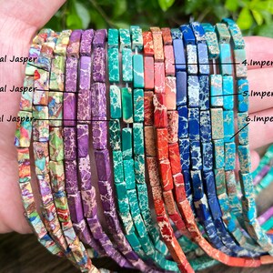 May include: Six strands of imperial jasper beads, each strand featuring a different color and pattern. The beads are rectangular and have a polished finish. The colors include green, purple, red, blue, and brown.