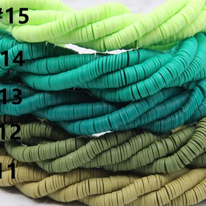 May include: A stack of five strands of colorful plastic beads. The beads are round and flat, and they are arranged in a gradient from light green to dark green. The strands are labeled with numbers 11 through 15.
