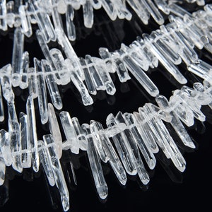 May include: A strand of clear quartz crystal points, also known as rock crystal, arranged in a staggered pattern. The points are various lengths and have a natural, raw finish.