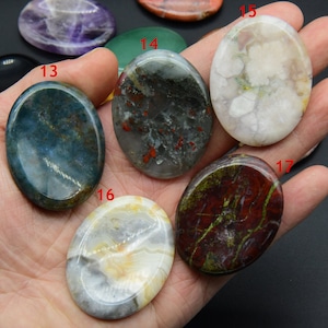May include: Seven oval-shaped polished stones in various colors and patterns, including green, white, red, and black. The stones are arranged in a hand, with the numbers 13, 14, 15, 16, and 17 visible.