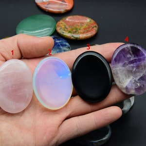 May include: Assortment of oval-shaped polished stones in various colors, including pink, white, black, purple, and green. The stones are smooth and have a natural, polished finish.