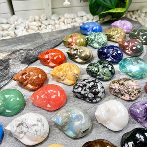 May include: A collection of 20+ sleeping cat figurines carved from various types of polished stones. The cats are in various colors, including red, green, blue, white, black, and brown.