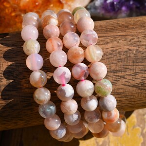 May include: A set of three bracelets made with pink, white, and green agate beads. The beads are round and have a natural, polished finish.