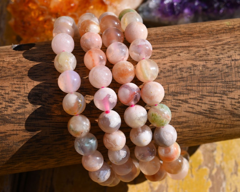 May include: A set of three bracelets made with pink, white, and green agate beads. The beads are round and have a natural, polished finish.