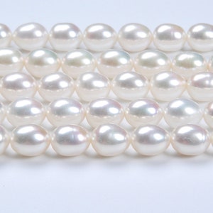 May include: A strand of white oval pearls, arranged in rows, showcasing their smooth, lustrous surface.