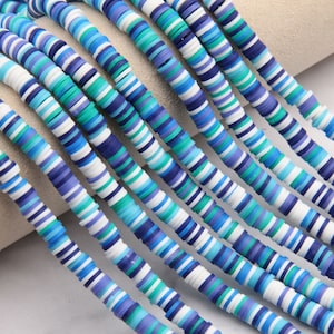 May include: A strand of colorful polymer clay beads. The beads are flat and round, with a striped pattern in shades of blue, white, and green.