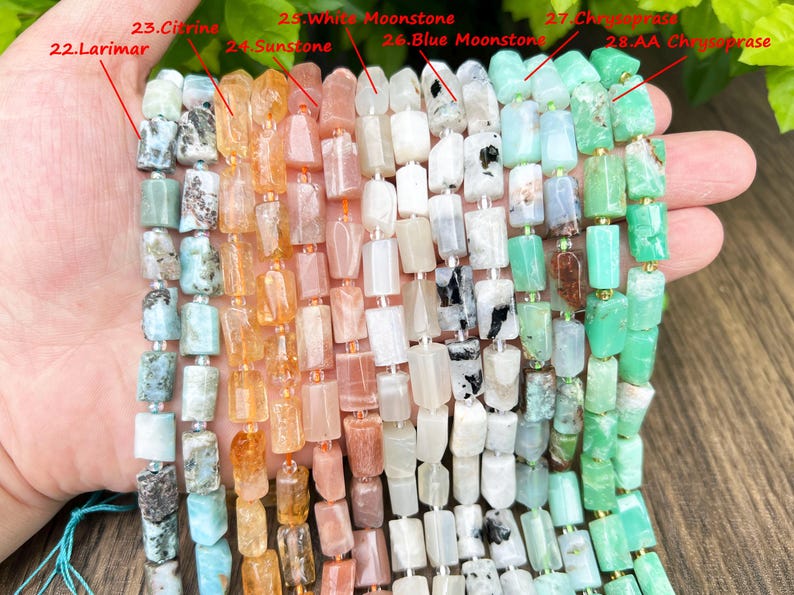 May include: A selection of gemstone beads in various colors, including Larimar, Citrine, Sunstone, White Moonstone, Blue Moonstone, and Chrysoprase. The beads are rectangular and strung together, showcasing a range of natural hues and textures. Ideal for jewelry making.