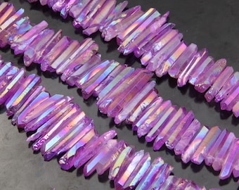 Puede incluir: Una hebra de puntas de cristal de cuarzo púrpura iridiscente, también conocidas como cuarzo aura, dispuestas en filas. Los cristales son lisos y pulidos, con una variedad de tamaños y formas.