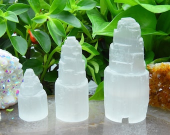 May include: Three white selenite crystal towers of varying sizes. The towers are stacked in a pyramid shape and have a smooth, polished finish.