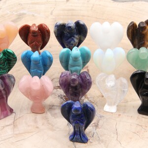 May include: A collection of 16 small angel figurines carved from various gemstones, including amethyst, rose quartz, clear quartz, black obsidian, tiger's eye, lapis lazuli, turquoise, malachite, and more.