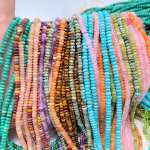 Puede incluir: Múltiples hilos de pequeñas cuentas de piedras preciosas redondas y facetadas en una vibrante gama de colores que incluye turquesa, naranja, rosa, morado, marrón y verde. Las cuentas están ensartadas en hilos finos, mostrando texturas naturales.