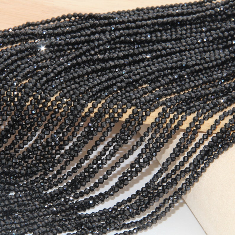 May include: A strand of black faceted beads, likely made of glass or crystal. The beads are small and uniform in size, creating a sleek and elegant look.