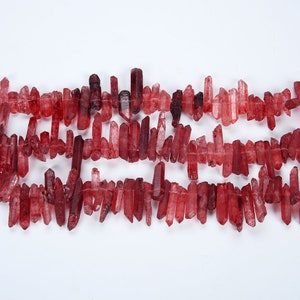 May include: A strand of red quartz crystal points, also known as red phantom quartz, arranged in rows. The crystals are translucent and have a reddish-brown hue.