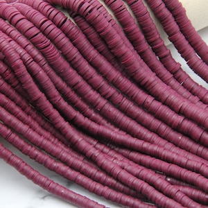 Puede incluir: Una hebra de cuentas de arcilla polimérica de color marrón. Las cuentas son planas y redondas, parecidas a monedas. Las cuentas están apiladas unas sobre otras, creando un efecto de capas.