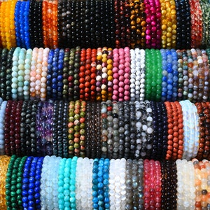 May include: A collection of colorful beaded bracelets made from various gemstones, including amethyst, agate, turquoise, and tiger's eye. The bracelets are stacked on top of each other, creating a vibrant and eye-catching display.