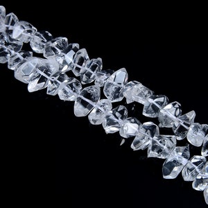 May include: A strand of clear quartz crystal beads, each bead is faceted and has a unique shape. The beads are strung on a clear thread and are arranged in a staggered pattern.