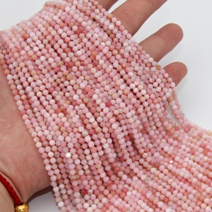 May include: A strand of pink opal beads, each bead is round and faceted. The beads are strung on a clear thread and are approximately 4mm in diameter.