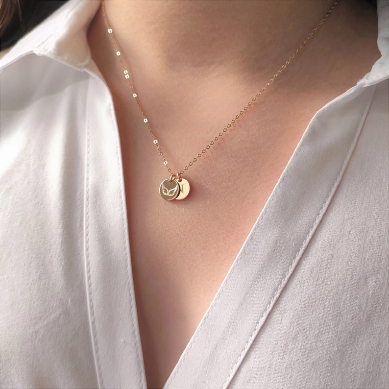 May include: A gold chain necklace with two small round pendants. The pendants feature a delicate butterfly design.