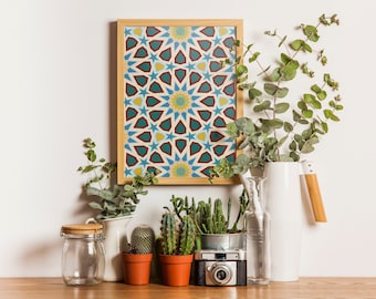 May include: A framed print with a geometric pattern in shades of blue, red, yellow, and white hangs on a white wall.  The print is surrounded by potted plants, including succulents and eucalyptus.