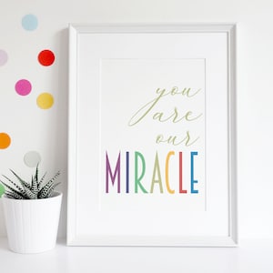 May include: White framed print with the text "you are our MIRACLE" in rainbow colors.