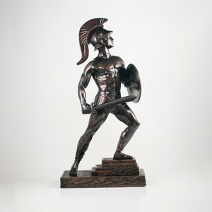 May include: A bronze statue of a warrior in a helmet and armor, holding a sword and shield. The warrior is standing on a tiered base.