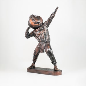 以下が含まれることがあります： かぼちゃの形をした頭をした漫画のキャラクターのブロンズ像で、