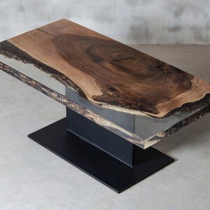 May include: A rectangular coffee table with a live edge walnut wood top and a clear epoxy resin fill. The table has a black metal base.