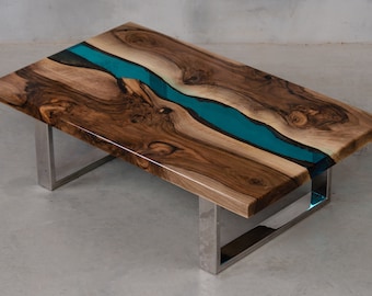 May include: A coffee table with a wooden top and a turquoise epoxy river running through the center. The table has a modern, minimalist design with a chrome metal frame.
