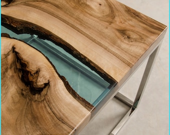 May include: A wooden table top with a clear blue resin inlay. The table has a stainless steel frame.