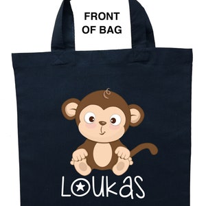 May include: A dark blue tote bag with a brown monkey illustration and the name "Loukas" in white with a star.