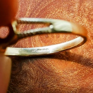 May include: Close-up of the inside of a silver ring with the inscription "925 000" on the band.
