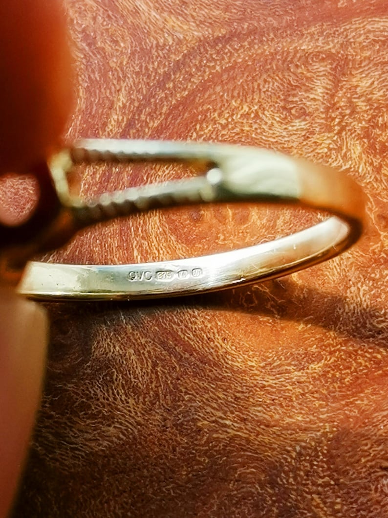 May include: Close-up of the inside of a silver ring with the inscription "925 000" on the band.
