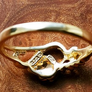 May include: A gold ring with a detailed design. The ring is marked "10K" and "GGG" on the inside.